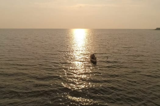 A fisherman in a boat in the sea against the sunset.