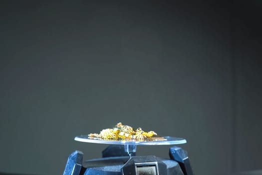 A golden scrap of old gold jewelry on electronic scales.