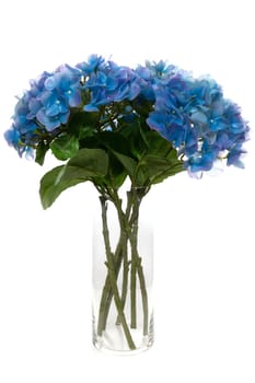 Elegant blue artificial flowers made of silicone and latex are arranged in a clear glass vase, bringing a touch of color and sophistication to any interior setting.