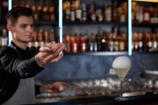 handsome barman is making cocktail with smoky air bubble at the bar