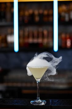 alcoholic cocktail with smoke at the bar. soft drink on the bar table.