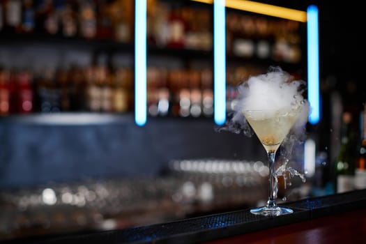 alcoholic cocktail with smoke at the bar. soft drink on the bar table. copy space