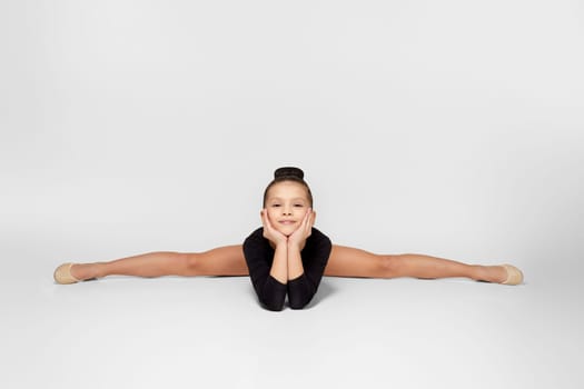 little child girl in black sportswear sitting on a transverse twine. Good stretching and gymnastics