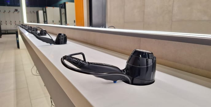 Sleek gym hairdryers lined up in modern fitness center locker room.