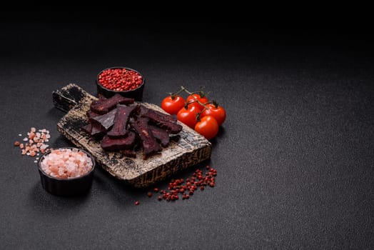 Horse meat sausage with salt, spices and herbs on a dark concrete background
