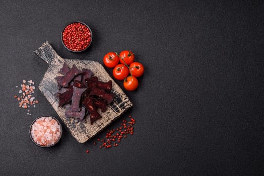Horse meat sausage with salt, spices and herbs on a dark concrete background