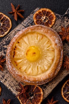 Sweet round tart with pineapple on a dark concrete background