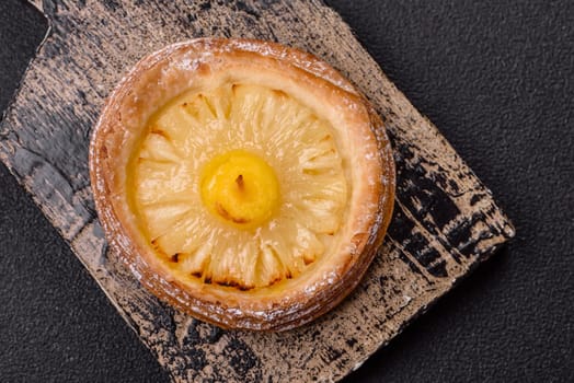 Sweet round tart with pineapple on a dark concrete background