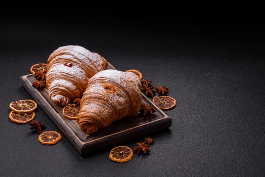 Sweet fresh crispy croissant with fruit filling on a dark concrete background