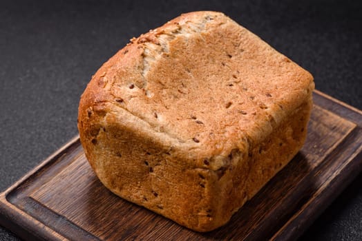 Brown bread with grains and seeds on a dark concrete background
