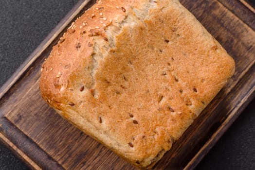 Brown bread with grains and seeds on a dark concrete background
