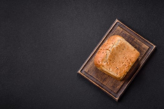 Brown bread with grains and seeds on a dark concrete background