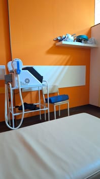 Modern medical examination room with equipment and bright orange walls.