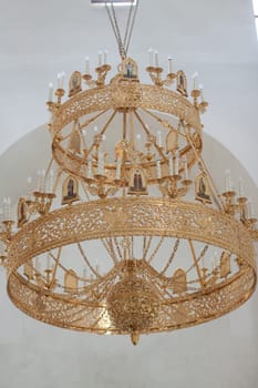 Ornate gold chandelier with candle holders in modern architecture.