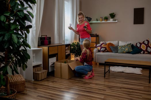 Two joyful children are exploring colorful boxes in a warm living room filled with fun, delightful toys