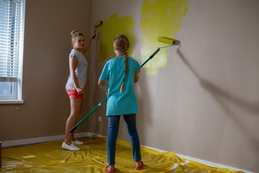 Children are joyfully and actively engaging in painting a bright and cheerful room with vibrant yellow hues