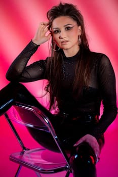 A striking fashion portrait featuring a model in a shimmering bodysuit against a vibrant pink backdrop.