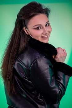 A young woman with long hair poses confidently in a leather jacket against an eyecatching vibrant backdrop