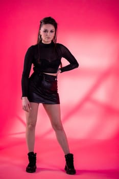 A stylish young model elegantly showcases modern fashion trends while posing against a bright pink backdrop