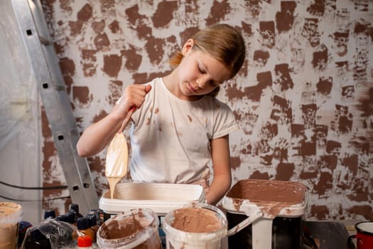 A focused young girl diligently participates in a home renovation project, using paint and various tools effectively