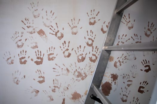 A colorful arrangement of vibrant handprints on a wall by a ladder, evoking creativity and expression