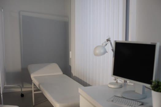 A calm and minimalist room that features a bed and a desk, illuminated by soft lighting and painted in neutral colors