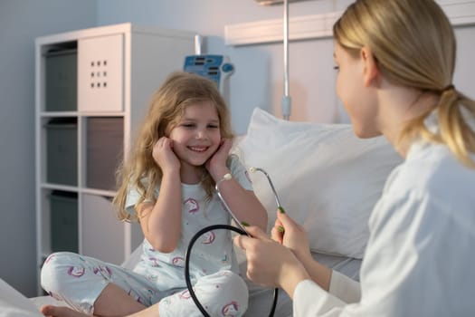 In a hospital setting, a young girl beams with joy while a caring nurse attentively listens using a stethoscope