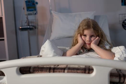 A young girl lies in a hospital bed, appearing deep in thought, seemingly lost in her own world of dreams