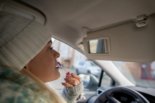 A stylish woman takes a moment to give herself a beauty touchup while comfortably sitting in her car