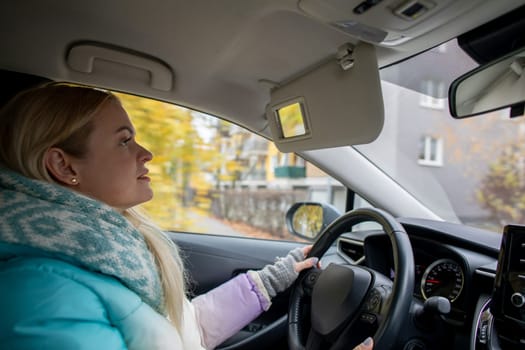 A joyful woman are smiling while driving on a refreshing and crisp autumn day, surrounded by stunning fall foliage