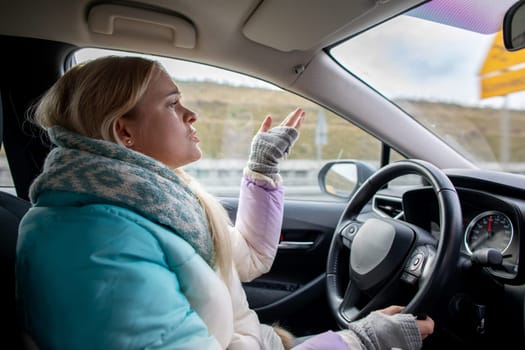 A woman, dressed comfortably in a cozy outfit, drives her car while expressing her heartfelt emotions on a chilly day