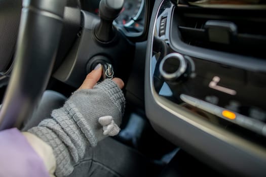 A gloved hand is carefully inserting a key into the ignition of a car, all set and ready to start the vehicle up