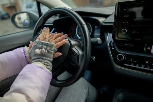 Warm, cozy gloves firmly grip the sleek steering wheel in a stylish automobile during a winter journey
