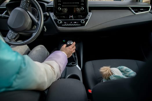 A beautifully designed car interior showcases a drivers hand poised on the gear shifter with a cute soft toy nearby