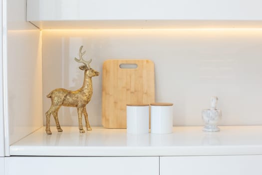 A golden figure of a deer stands in the kitchen, on a white table. Close up