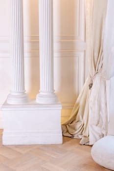 Elegant white interior design with classic columns and luxurious drapes.