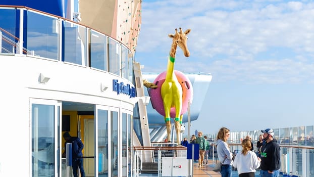 A yellow giraffe sculpture stands on Royal Caribbean cruise ship s deck with a blue sky in the background. New York NY USA - 09.02.2024