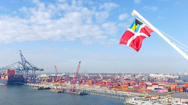 Vibrant Industrial Portside Scene Featuring Large Docked Ship and Billowing Yellow Flag in Wind. New York NY USA - 09.02.2024.
