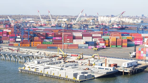 Cargo containers stacked in a shipping yard near the sea with a city in the background. New York NY USA - 09.02.2024.