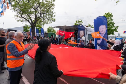 Istanbul, Turkey - May 3 2023: AK Party supporters waving a big Turkish flag in front of AK Party tent in the neighbourhood of Uskudar during 2023 elections