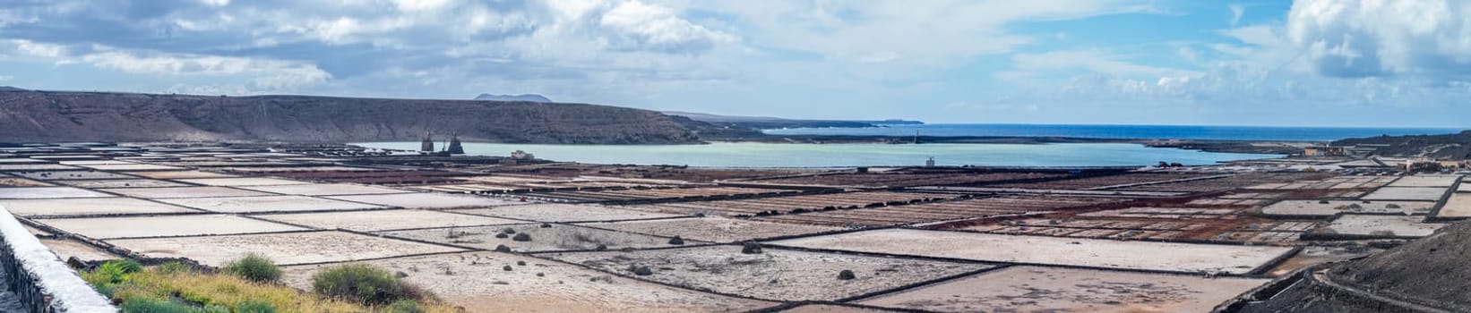 Salt pans line the coast, blending industry and natural beauty under a vast sky.