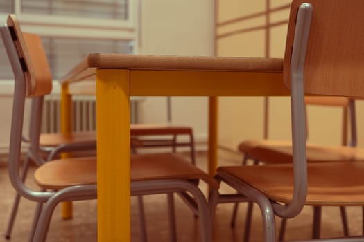 A bright classroom design featuring a yellow-legged table and metal-framed chairs arranged in an inviting learning environment, perfect for educational settings.