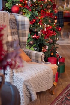 Cozy living room with festive christmas tree and plush armchair.