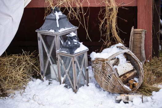 Winter lanterns in snowy rustic setting with basket and logs.