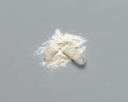 Opened Medical capsule to show white powder on grey top view. Alternative preventive medicine and healthcare, taking dietary supplements and vitamins