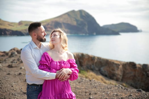 Tourists embracing on a cliff overlooking the ocean and mountains in ponta de s o louren o, madeira