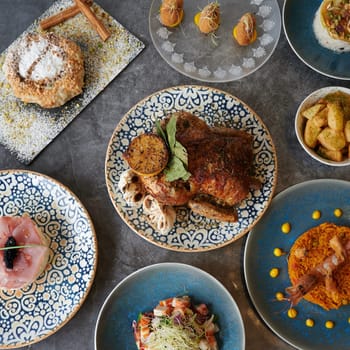 A table full of food with a blue plate in the middle. The plate has a chicken on it