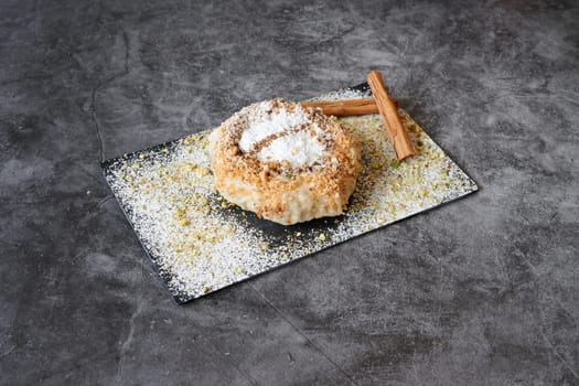 A dessert with a cinnamon stick on top of it. The dessert is on a black and white plate