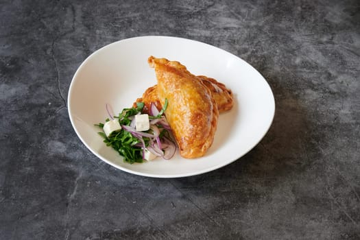 A plate of food with a side of salad. The plate is white and the food is brown