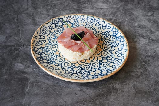 A plate of food with a small piece of meat and a small piece of blackberry. The plate is blue and white